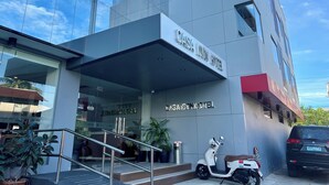 The exterior of Casa Ion Hotel with a modern glass facade, a visible entrance, and a parking area with a scooter and a car. - Casa Ison Hotel (Sablayan)