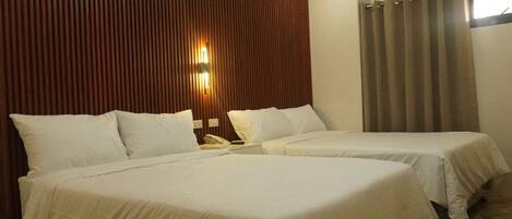 Habitación de hotel con dos camas, un panel de pared de madera, teléfono sujeto a la pared y una ventana con cortinas.