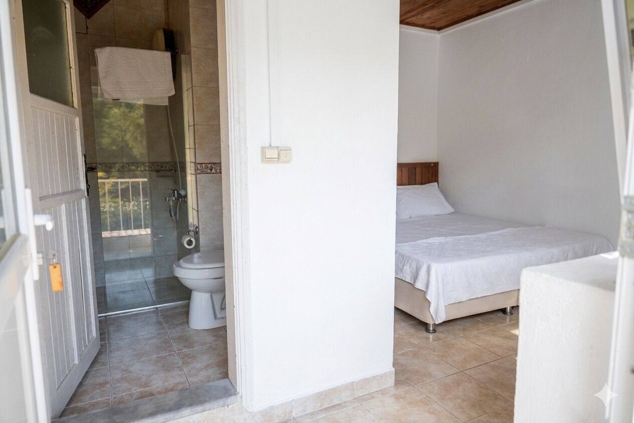 Un dormitorio con cama, un baño con inodoro y ducha, y una puerta que da a un espacio al aire libre.