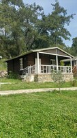 Una baita di legno con fondamenta in pietra, un portico con ringhiere bianche e un muro in pietra.