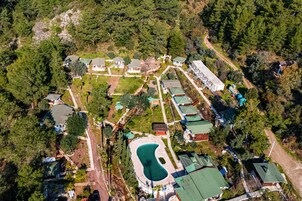 An aerial view of a residential area with multiple houses, a swimming pool, and a winding road.