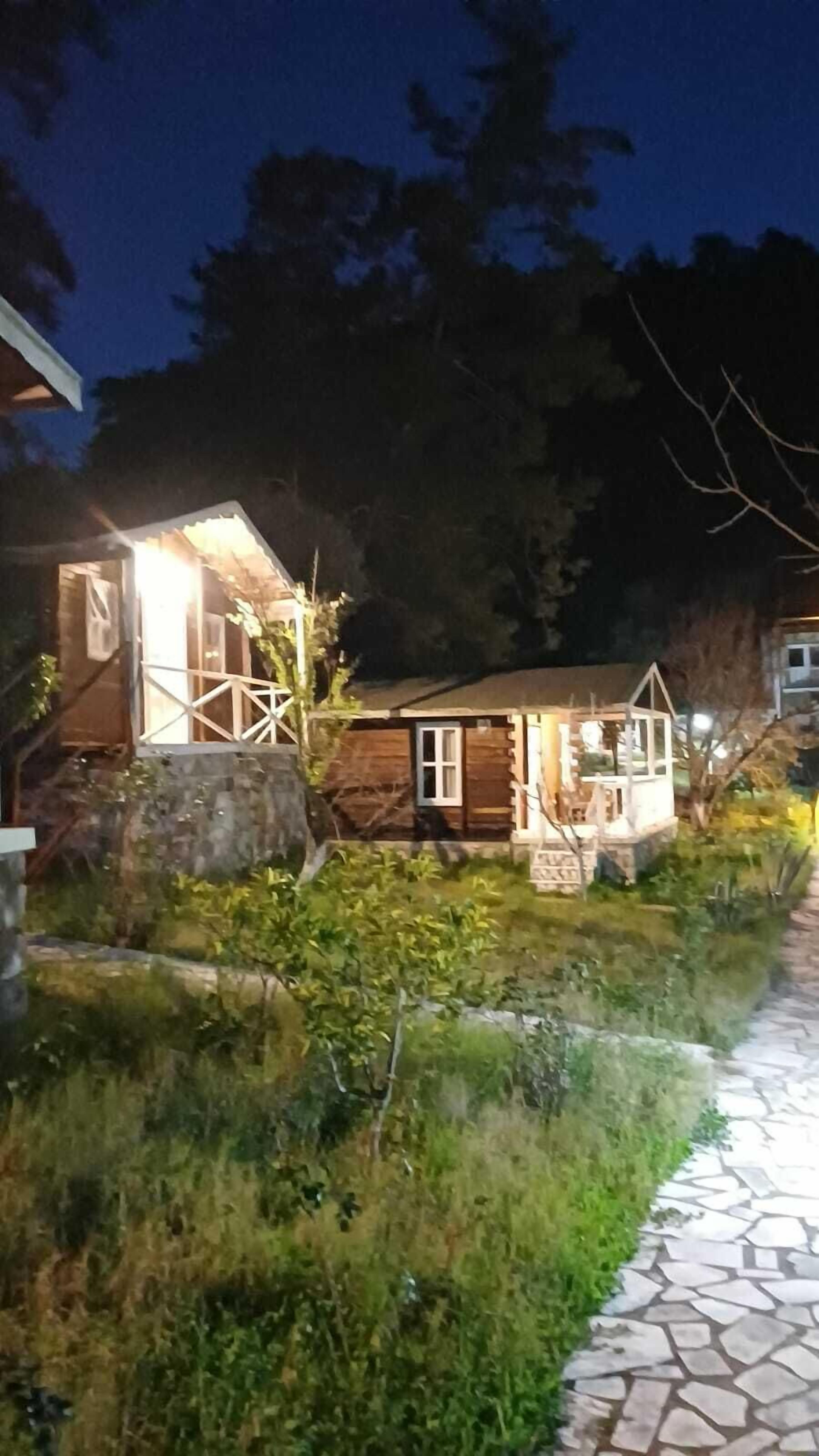 A wooden cabin with a stone foundation, a porch, and a small attached structure.