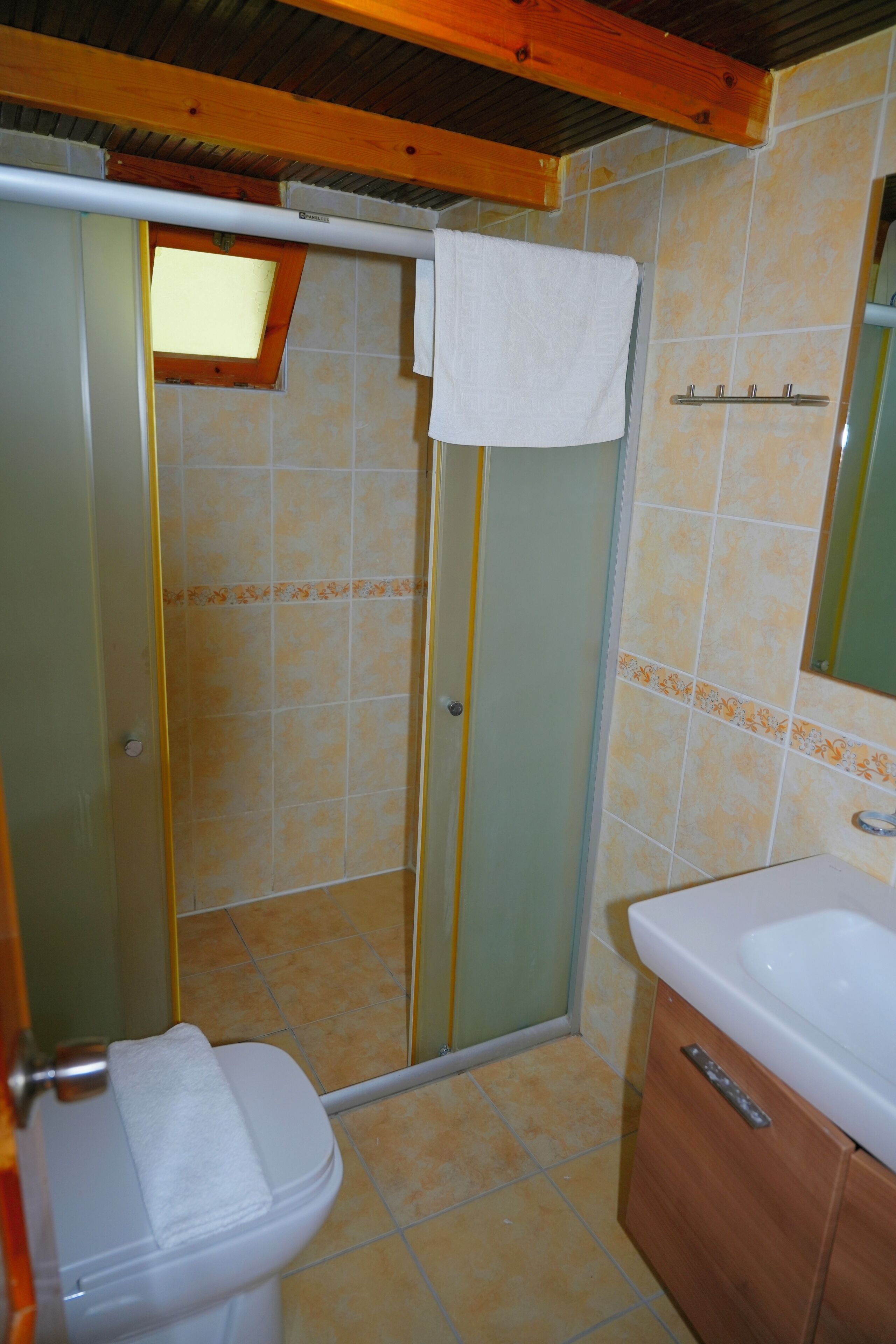 A bathroom with a toilet, a shower enclosure, and a sink.