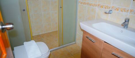 Un baño con inodoro, cabina de ducha y lavabo con espejo.