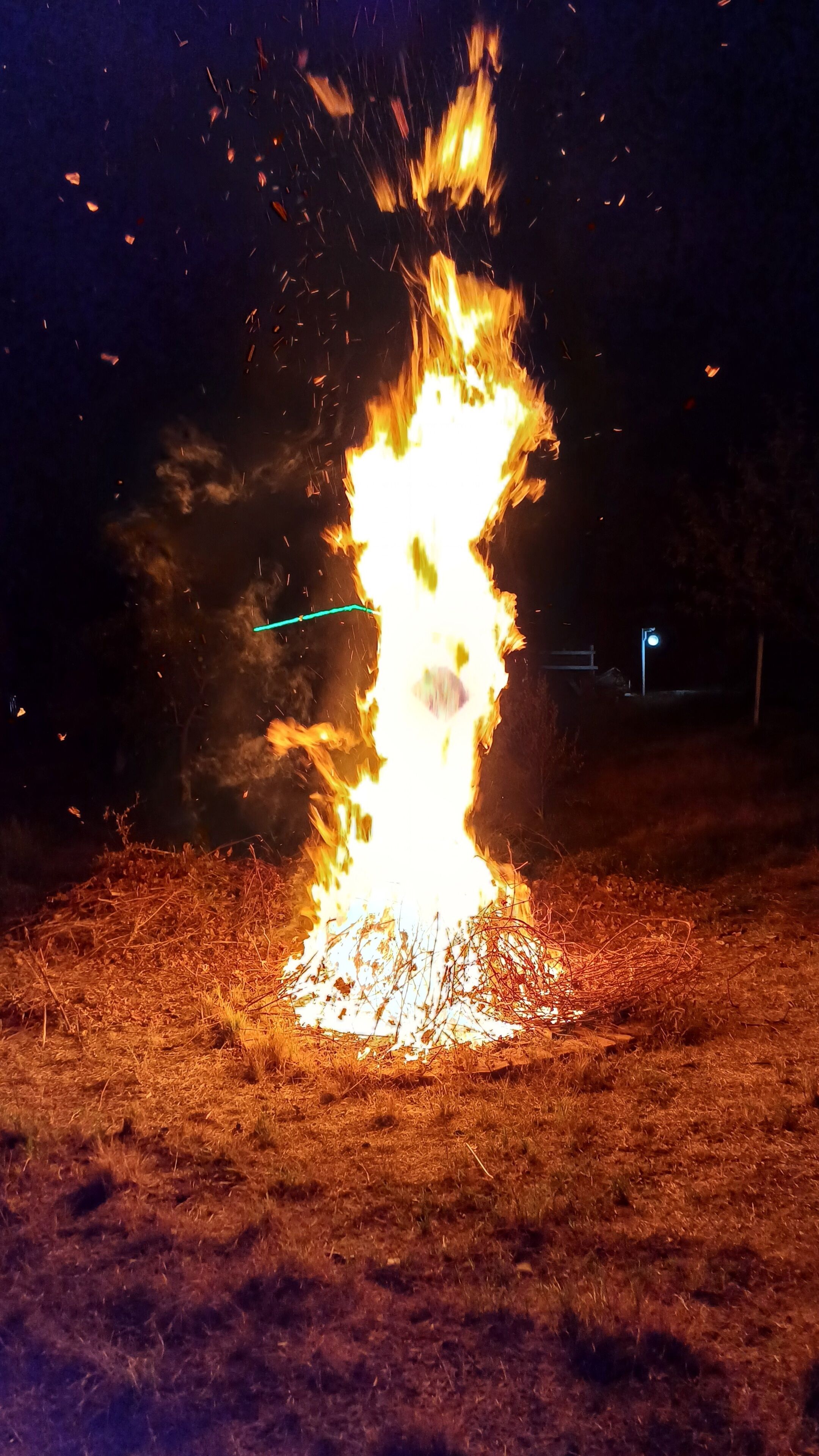 A fire burning in an open field at night.