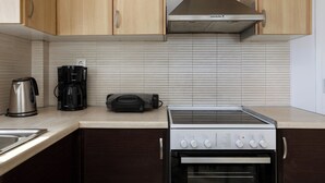 Une cuisine dotée de meubles en bois, d’une hotte en acier inoxydable, d’une machine à café, d’un grille-pain et d’un four.