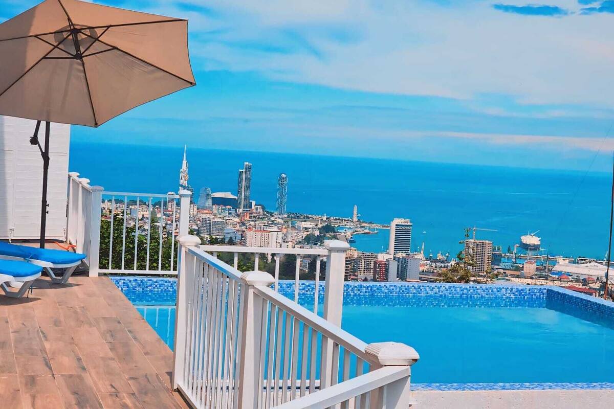 A balcony with a pool, a city view, and a beach.