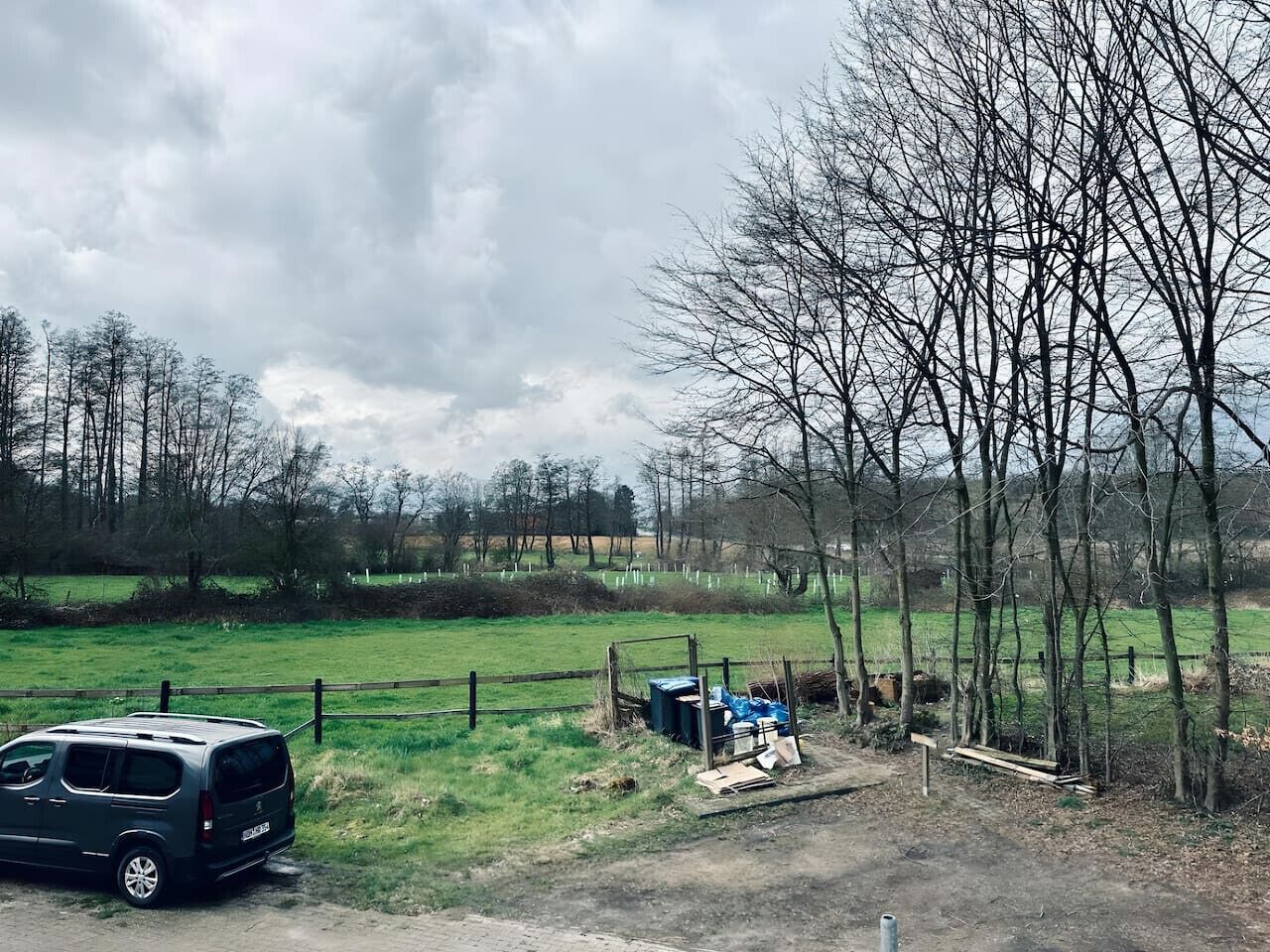 Un paysage rural avec une voiture garée, une clôture en bois et un banc.