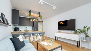 Ein modernes Wohnzimmer mit Sofa, Couchtisch und Wand-Fernseher.