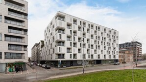 Ein modernes, mehrgeschossiges Gebäude mit einer rasterförmigen Fassade, großen Fenstern und einem flachen Dach.