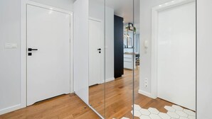 Ein Flur mit weißen Türen, Holzböden und einem sechseckigen Fliesendesign nahe den Türen.