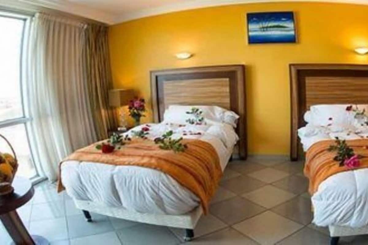 A hotel room with two beds, a large window, and a view of the outdoors.