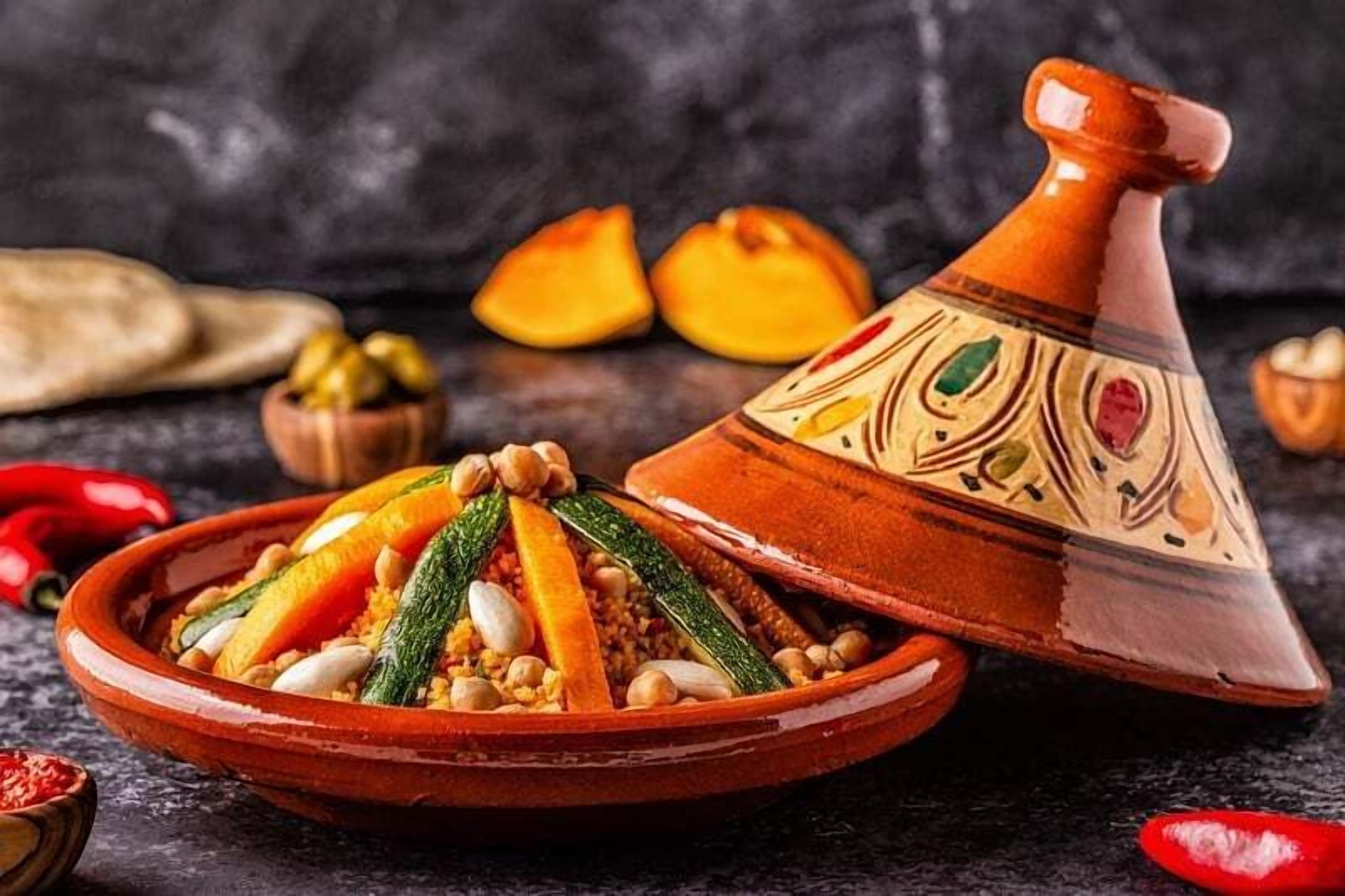 Un tajine marocain traditionnel, présenté dans un pot en argile décoratif, accompagné d’un plat de service contenant un plat coloré à base de légumes et de viande, le tout sur un fond rustique.