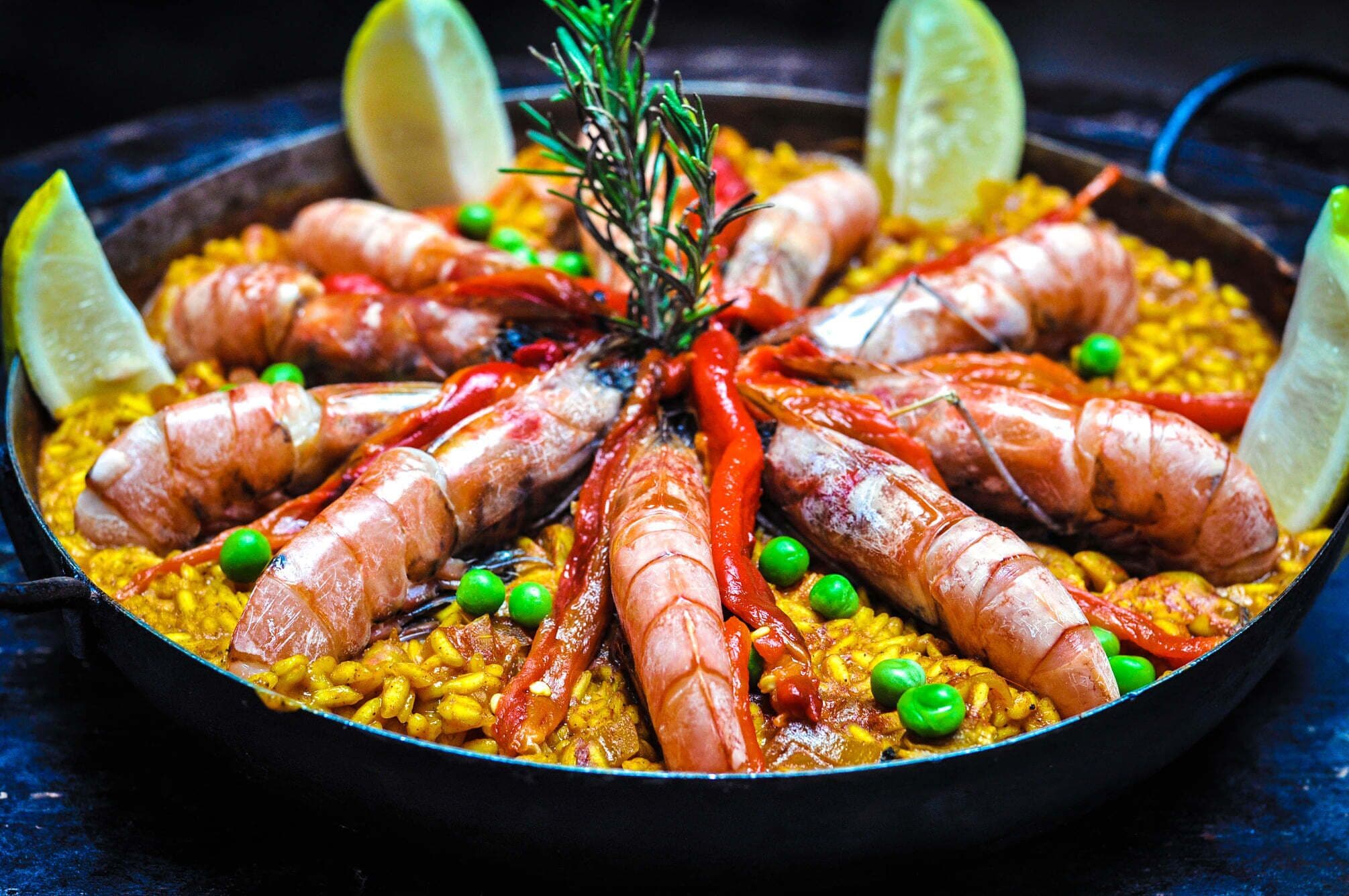 Una paella de mariscos con camarones y guisantes.