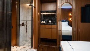 Een moderne badkamer met een inloopdouche, een wastafel met spiegel, en een bed met uitzicht.