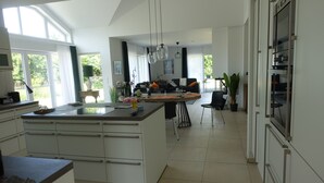 Una cocina moderna con una isla central, armarios blancos y un comedor con mesa y sillas.
