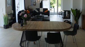 Un comedor moderno con una mesa redonda de madera, sillas negras y una lámpara colgante.