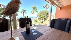 Una mesa con una botella de vino, dos copas y una escultura de pájaro.