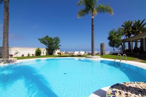 A clear blue pool with lounge chairs, palm trees, and a view of the ocean. - Villa La Perla Exotica
Your luxury and specious Tenerife ocean view paradise! (Los Realejos)