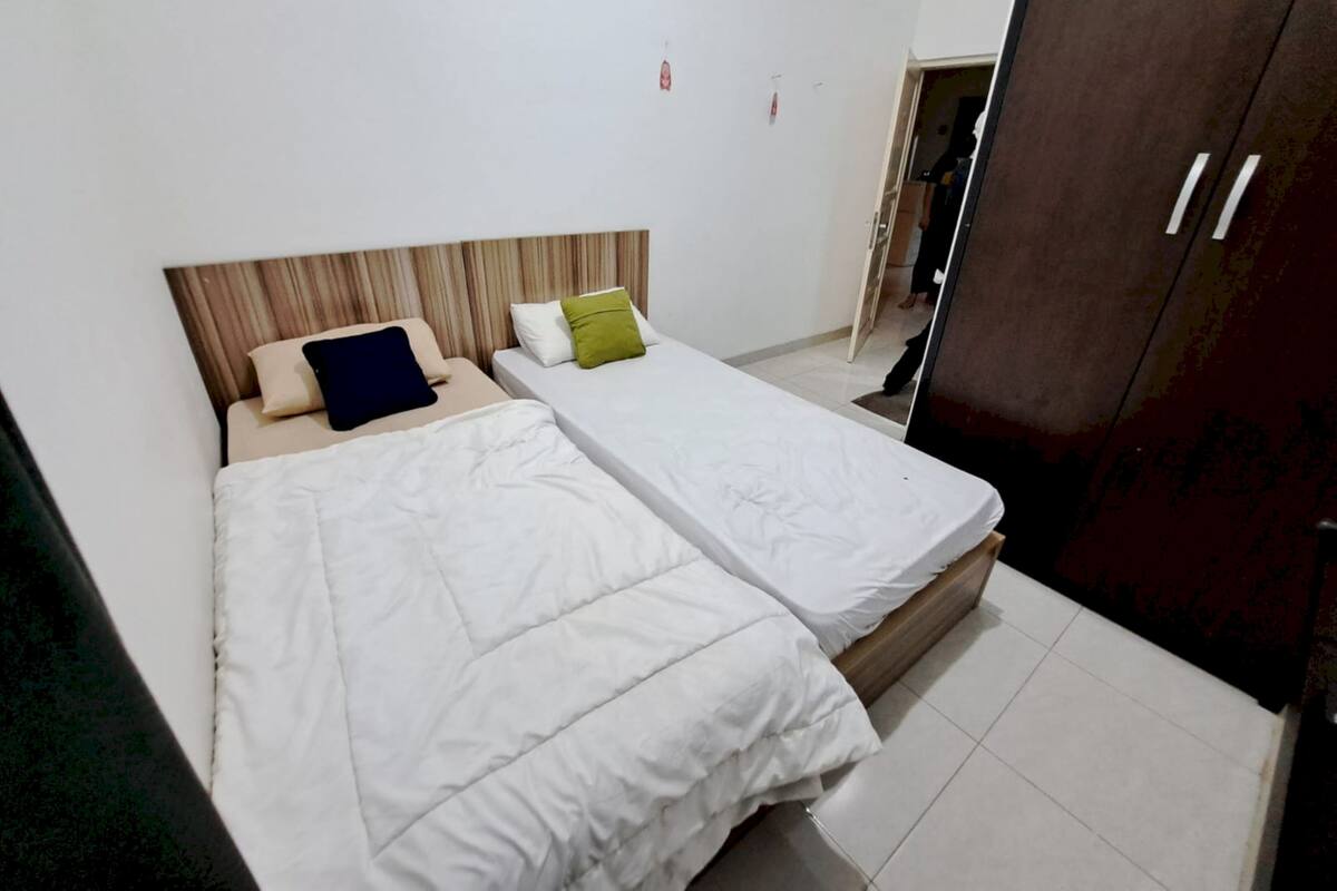 A room with two single beds, a wooden headboard, and a wardrobe.