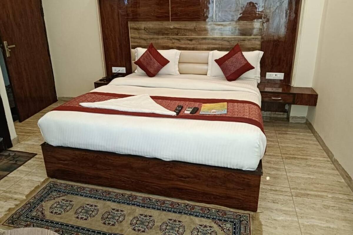 A neatly made bed with a wooden headboard, a patterned rug, and a bedside table with a lamp.