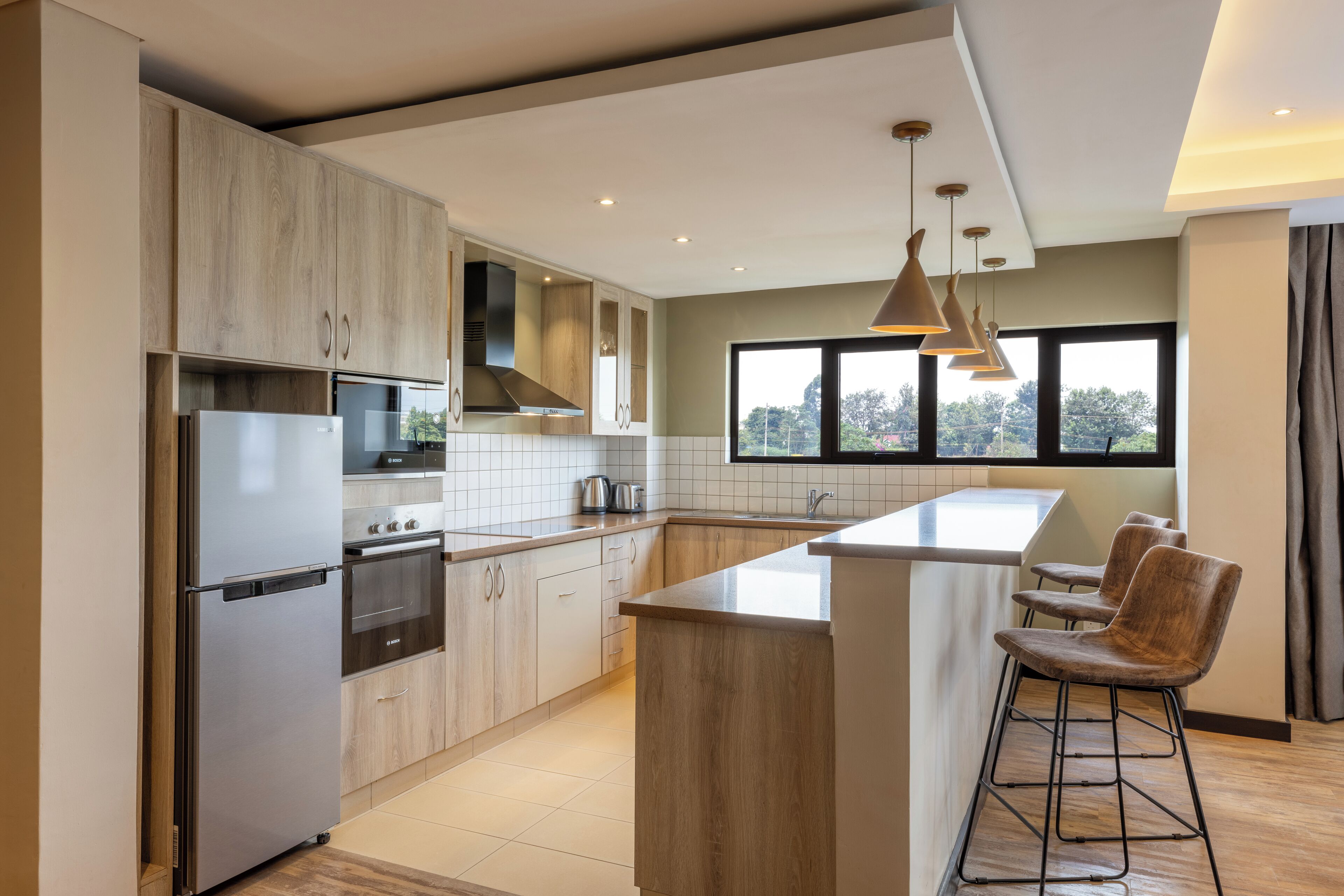 A modern kitchen with a central island, stainless steel appliances, and a large window providing natural light.