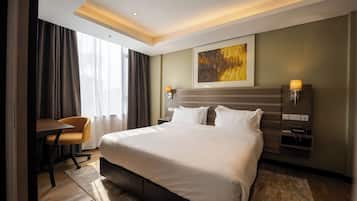 Ein Hotelzimmer mit einem großen Bett, einem Schreibtisch, einem Stuhl und einem Bild an der Wand.