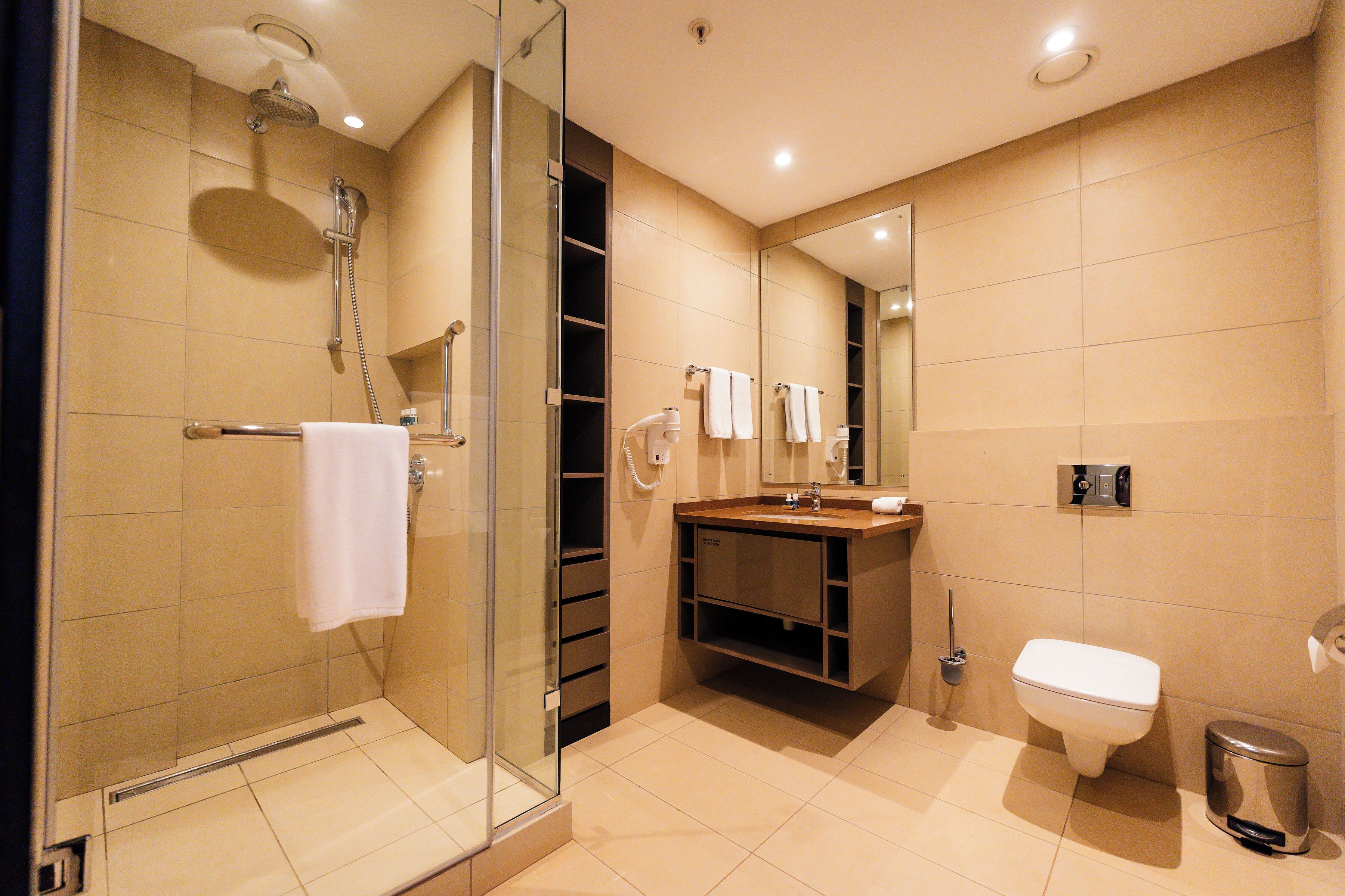 Un bany modern amb dutxa de vidre, un lavabo amb mirall i un vàter.