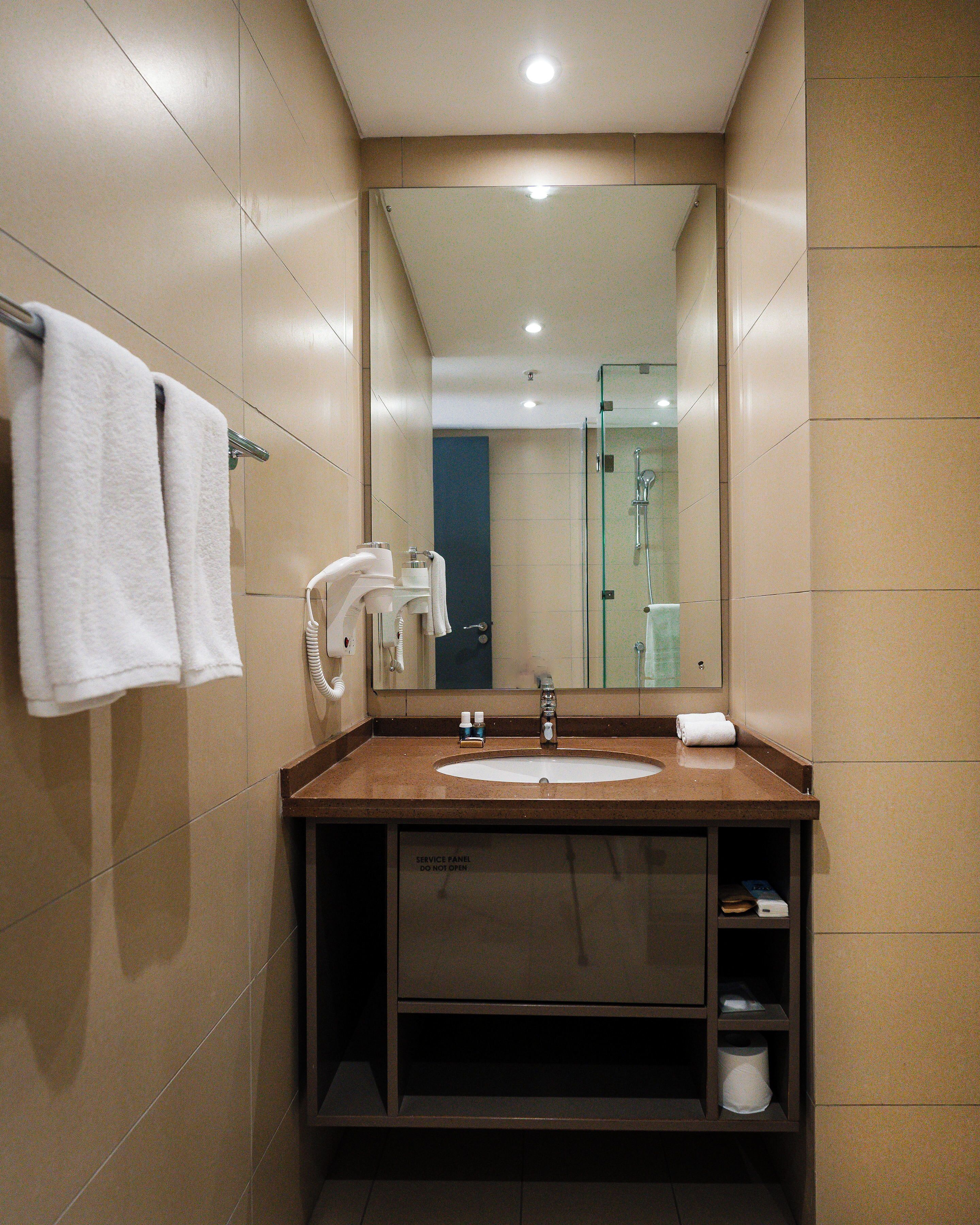 Une salle de bain moderne équipée d’un lavabo, d’un miroir, d’un porte-serviettes et d’une douche à parois en verre.