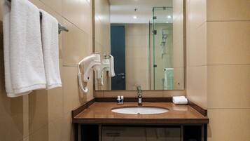 Une salle de bain moderne équipée d’un lavabo, d’un miroir, d’un porte-serviettes et d’une douche à parois en verre.