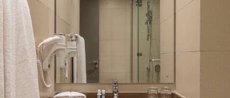 A bathroom with a sink, mirror, towel rack, and a glass shower enclosure.