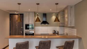 Une cuisine moderne dotée d’un îlot central, de luminaires suspendus et de tabourets de bar.
