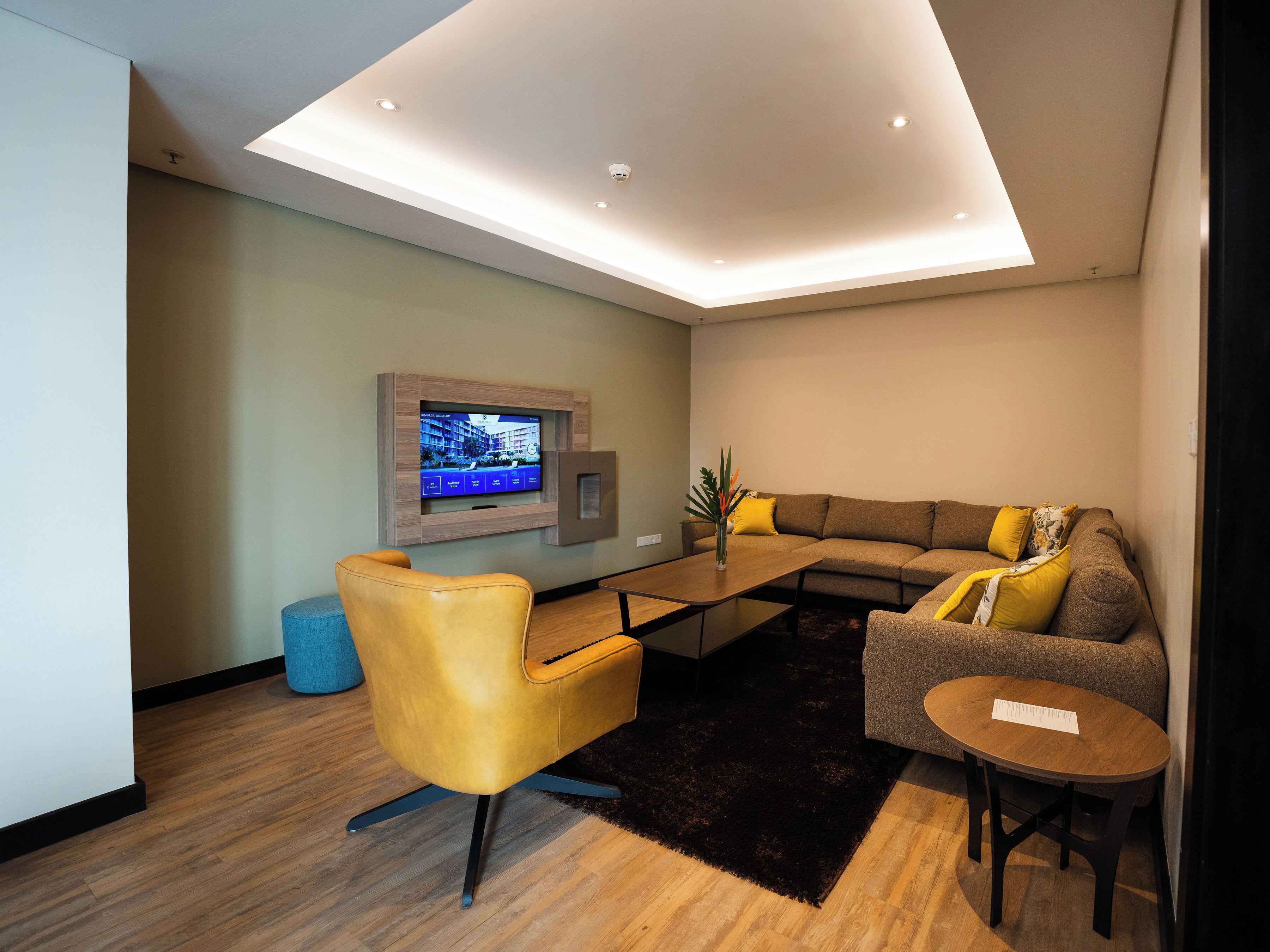 A modern living room with a flat-screen TV mounted on the wall, a sofa, a coffee table, and a chair.