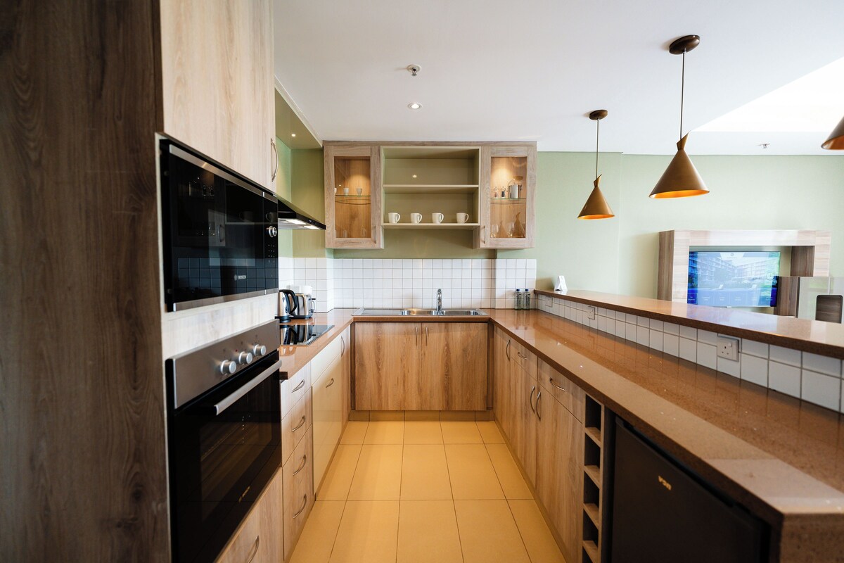 Une cuisine moderne avec des meubles en bois, un four encastré et des luminaires suspendus.