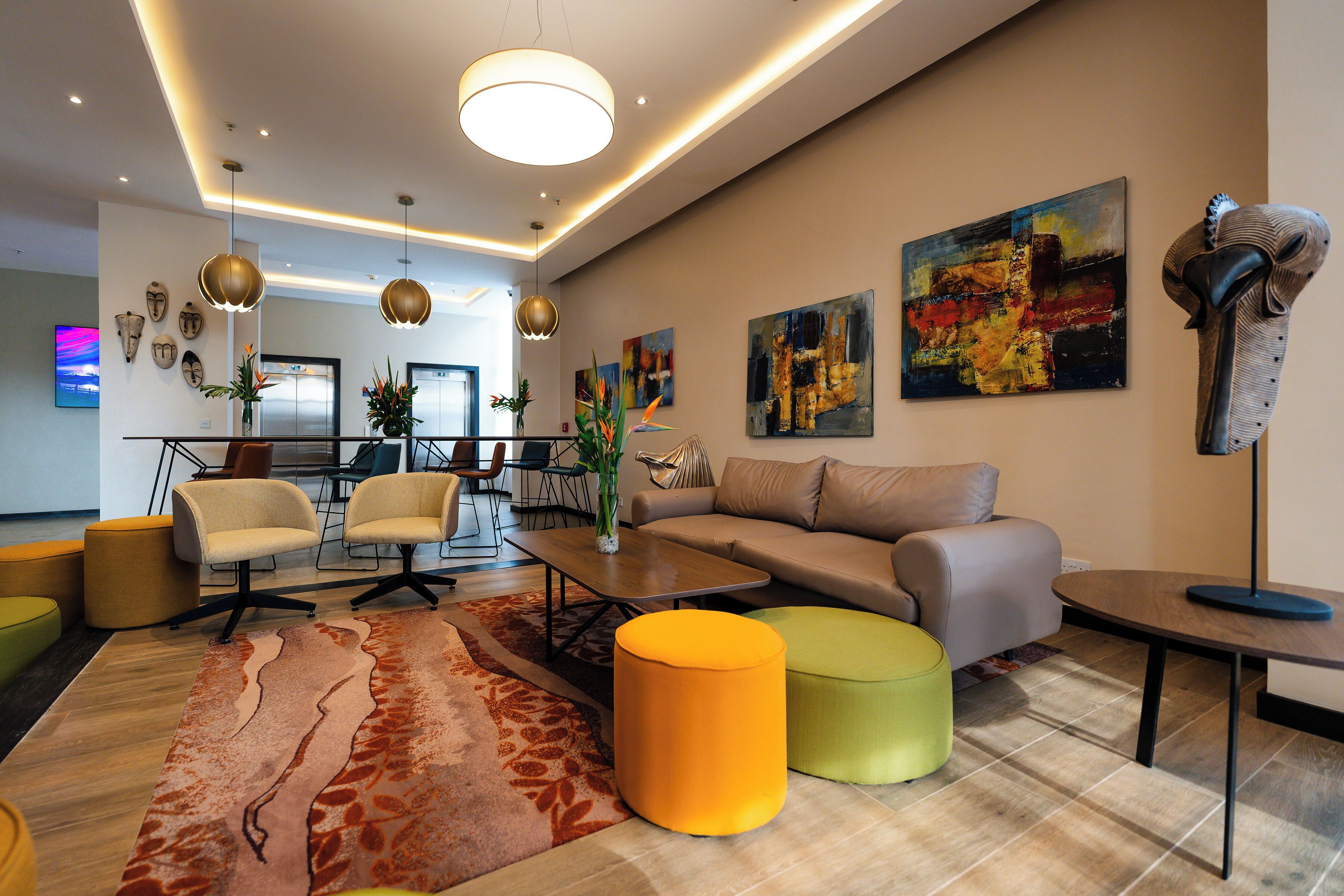 A modern living room with a sofa, ottomans, a coffee table, and artwork on the walls.