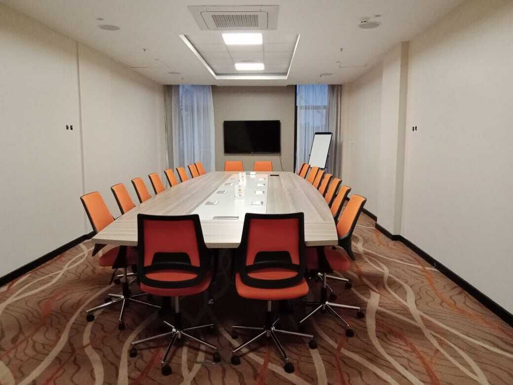 Une salle de conférence équipée d’une longue table, de nombreuses chaises, d’un téléviseur à écran plat et d’un tableau blanc.