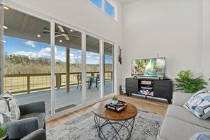 Un salón espacioso con una televisión grande, asientos cómodos y vistas al exterior.