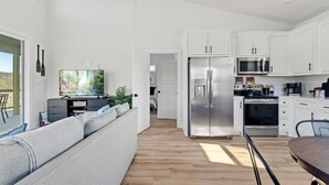 A modern kitchen with white cabinets, stainless steel appliances, and a wooden floor. - War Eagle Creek Retreat- Cabin on the Creek- Private but close to everything (HUNTSVILLE)