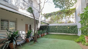 A courtyard with artificial grass, potted plants, and a wall covered in climbing plants. - Kalithea Gardenspot (Kallithea)