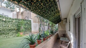 A covered outdoor area with a row of potted plants, a small table, and chairs. - Kalithea Gardenspot (Kallithea)