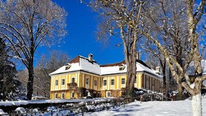 Ein großes, gelbes Gebäude mit einer symmetrischen Fassade, zahlreichen Fenstern und einem zentralen Schornstein.