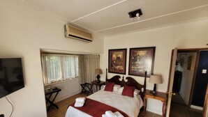 Una habitación de hotel con una cama, televisión, ventana con cortinas, escritorio y puerta.