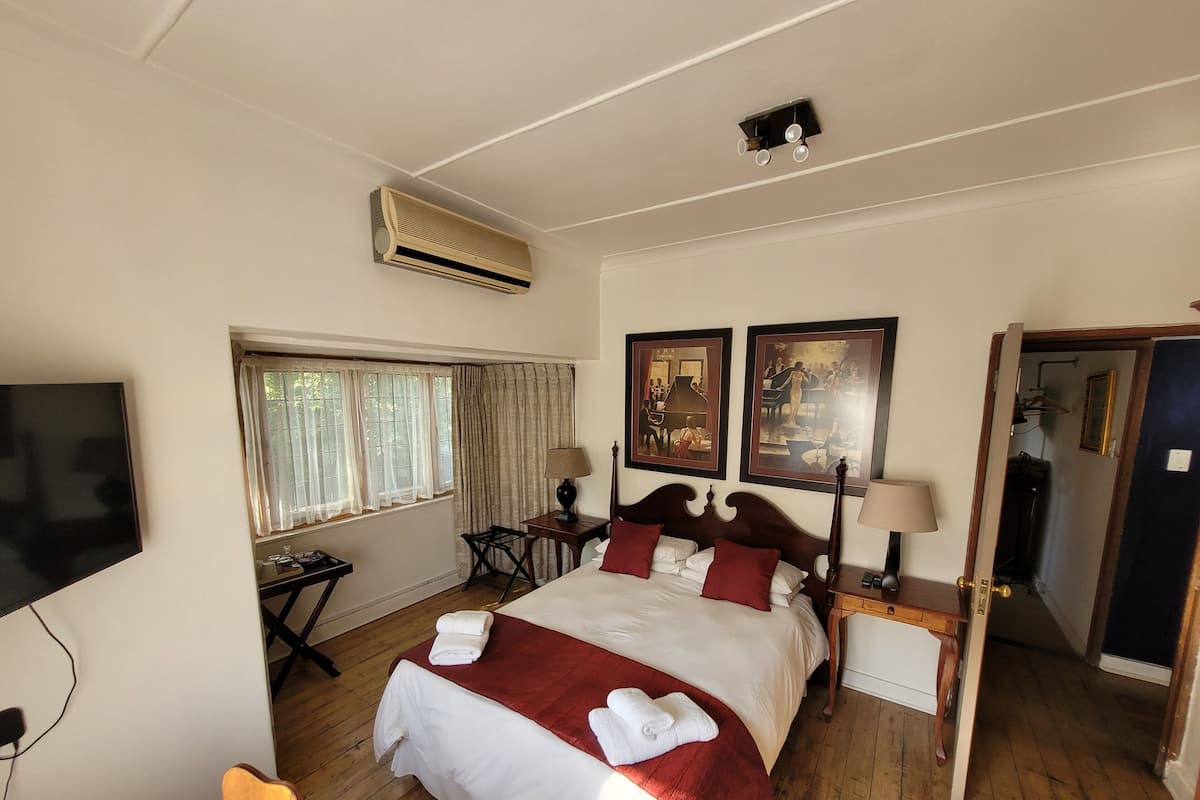 Una habitación de hotel con una cama, televisión, ventana con cortinas, escritorio y puerta.