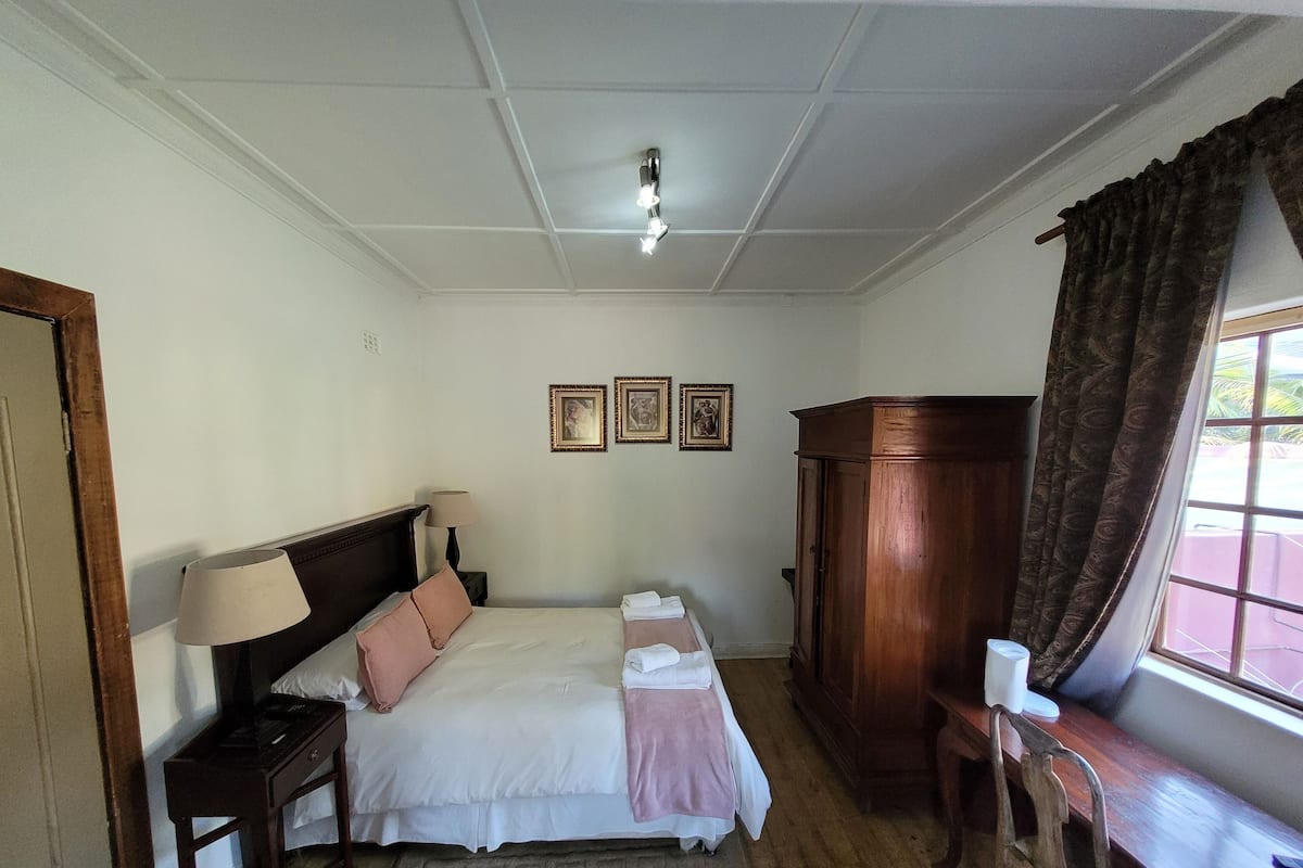 Un dormitorio ordenado con cama, mesitas de noche, armario y ventana con cortinas.