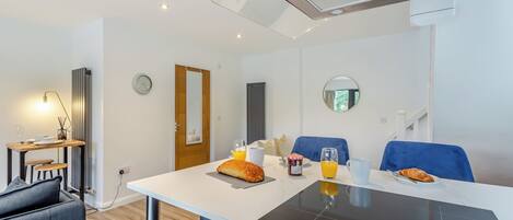 A modern kitchen with a built-in induction cooktop, a dining area with a table and chairs, and a seating area with a sofa.