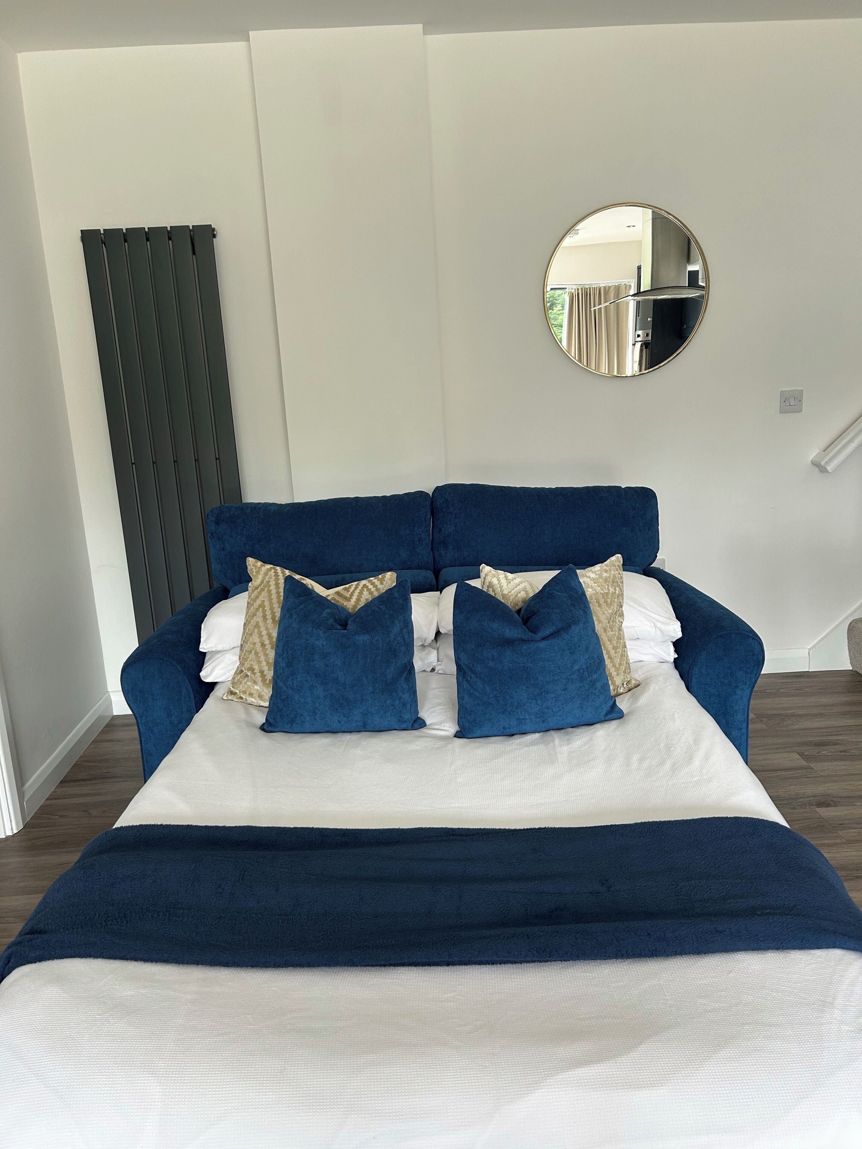 A bed with a dark blue headboard, white bedding, and blue pillows.