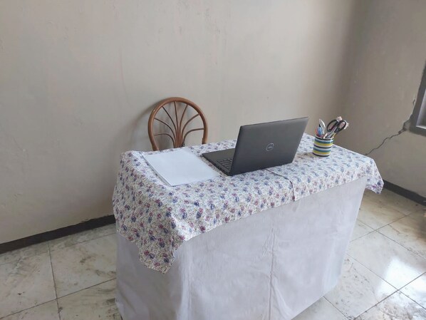 A small table with a laptop, a notepad, and a cup with pens.
