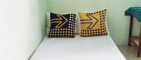 A bed with two pillows featuring geometric patterns.