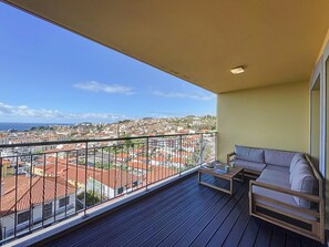 A balcony with a view of a cityscape, a sofa, and a small table. - The View by Atlantic Holiday (Funchal)