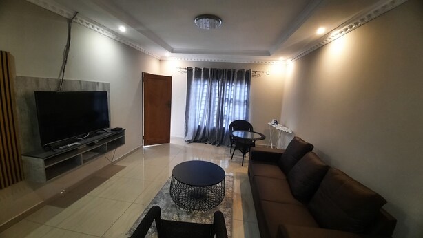A living room with a TV, sofa, coffee table, and a dining area with chairs and a table.